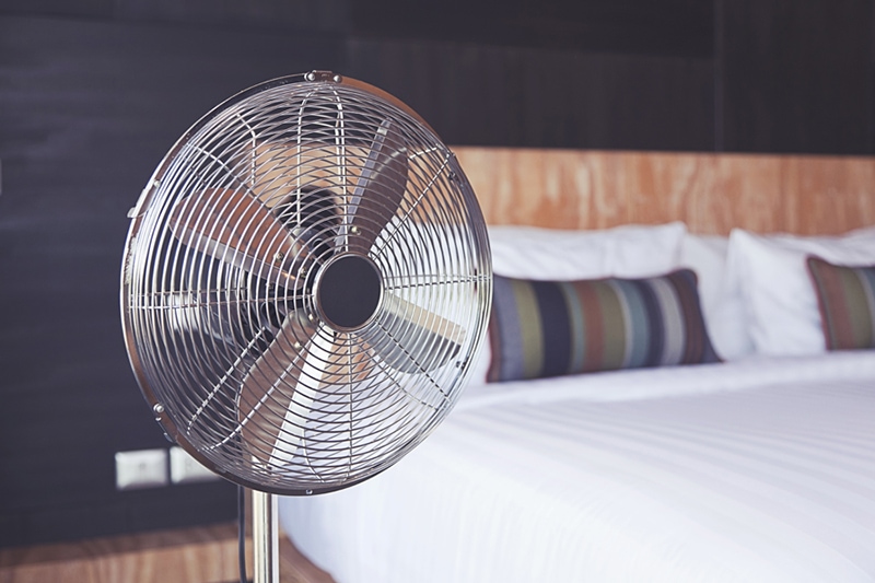 Old electric fan near the bed in the room.
