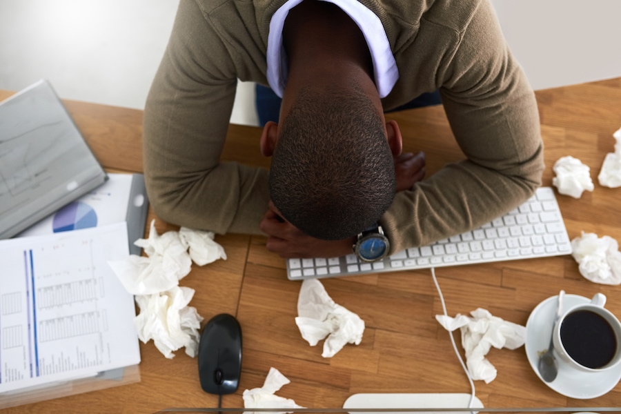 High angle shot of a young businessman feeling ill at his work desk