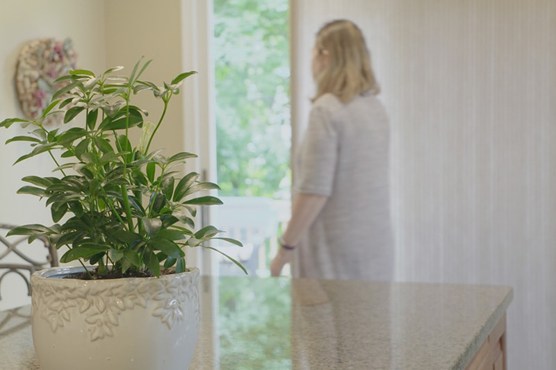 a woman standing in front of a kitchen with a plant in a pot.