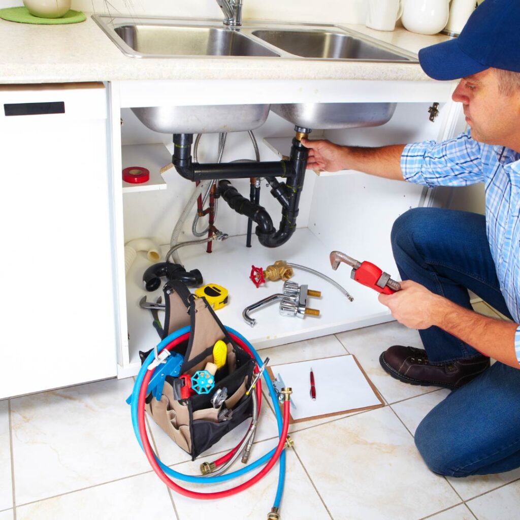 Plumber fixing sink with tools and parts