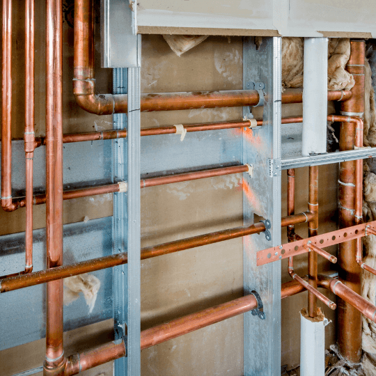Coper plumbing pipes in wall of building