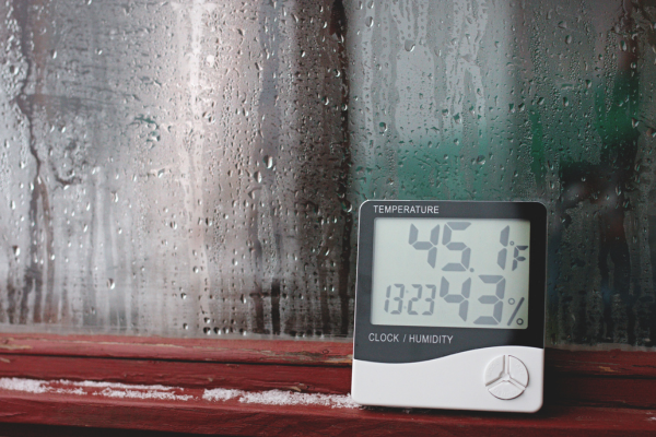 Measurement of air temperature, dew point, humidity with a device (hygrometer), against a background with condensation on the glass, high humidity